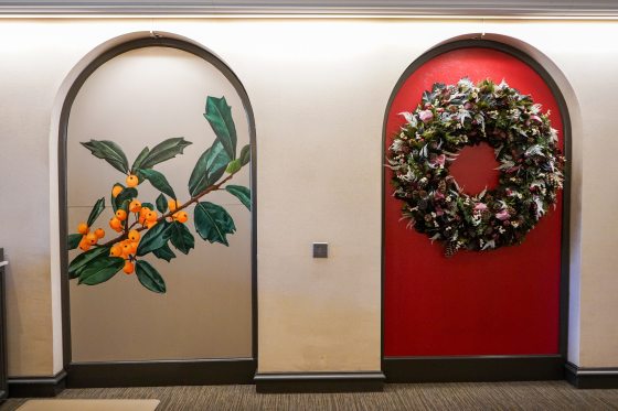 A mural of a branch of yellow berries inset in an arch.